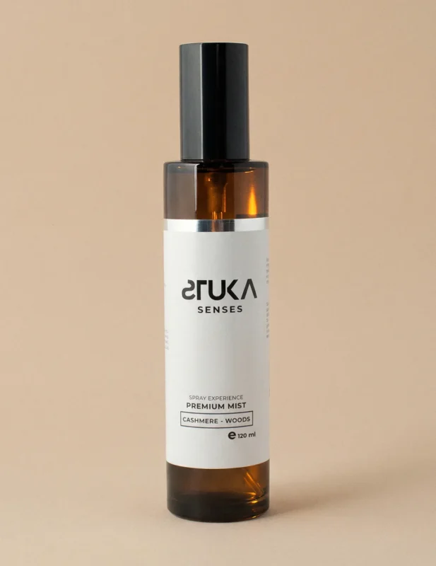 Elegante botella de spray aromatizante sobre suave tela de cachemira y madera STUKA SENSES